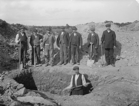Old photo of a group of dirty men digging a grave